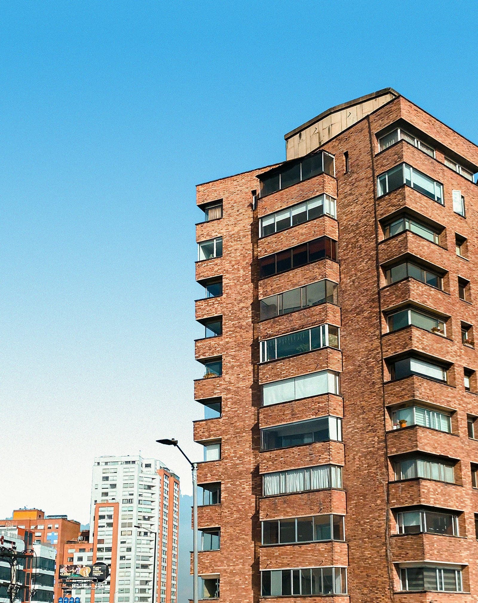 Torre residencial de ladrillo en Bogotá, con balcones cerrados en vidrio